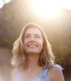 Smiling woman looking upward in warm natural sunlight