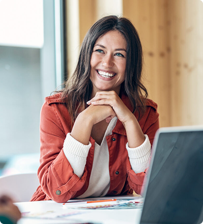 Smiling woman seated at a desk with a laptop